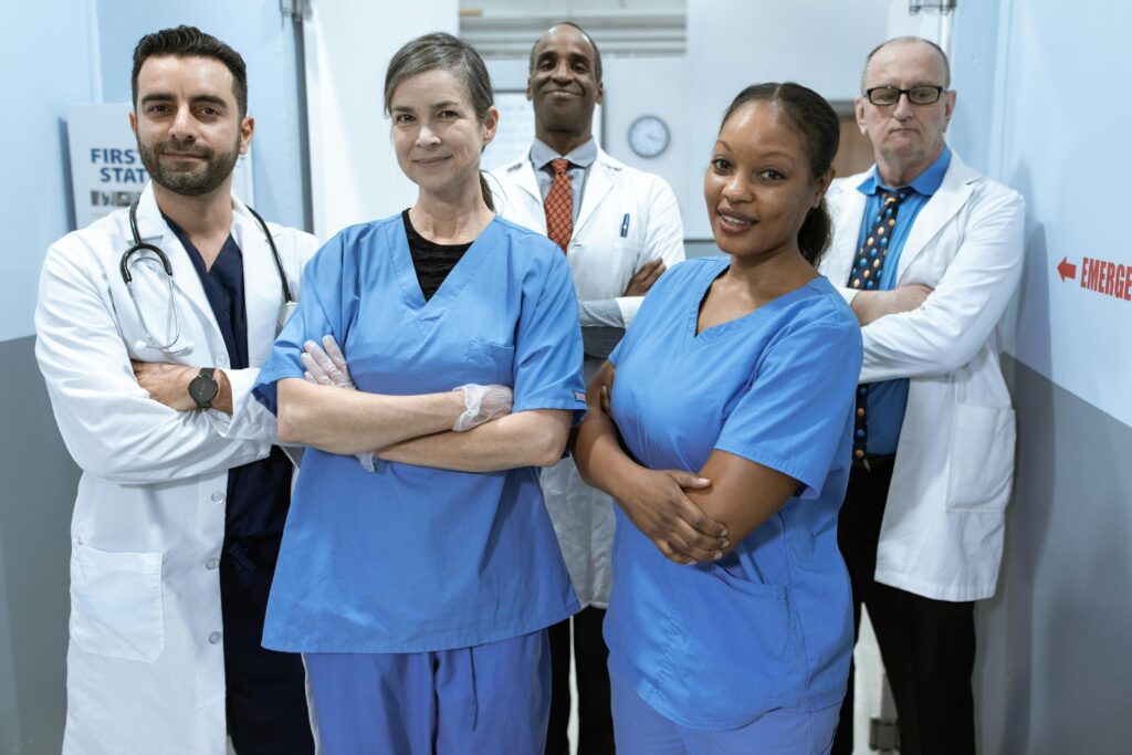 pexels-photo-6129507-6129507 A diverse team of doctors and nurses smiling confidently in a hospital setting.